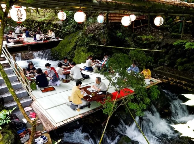 渓流の上の川床で食事をする人々